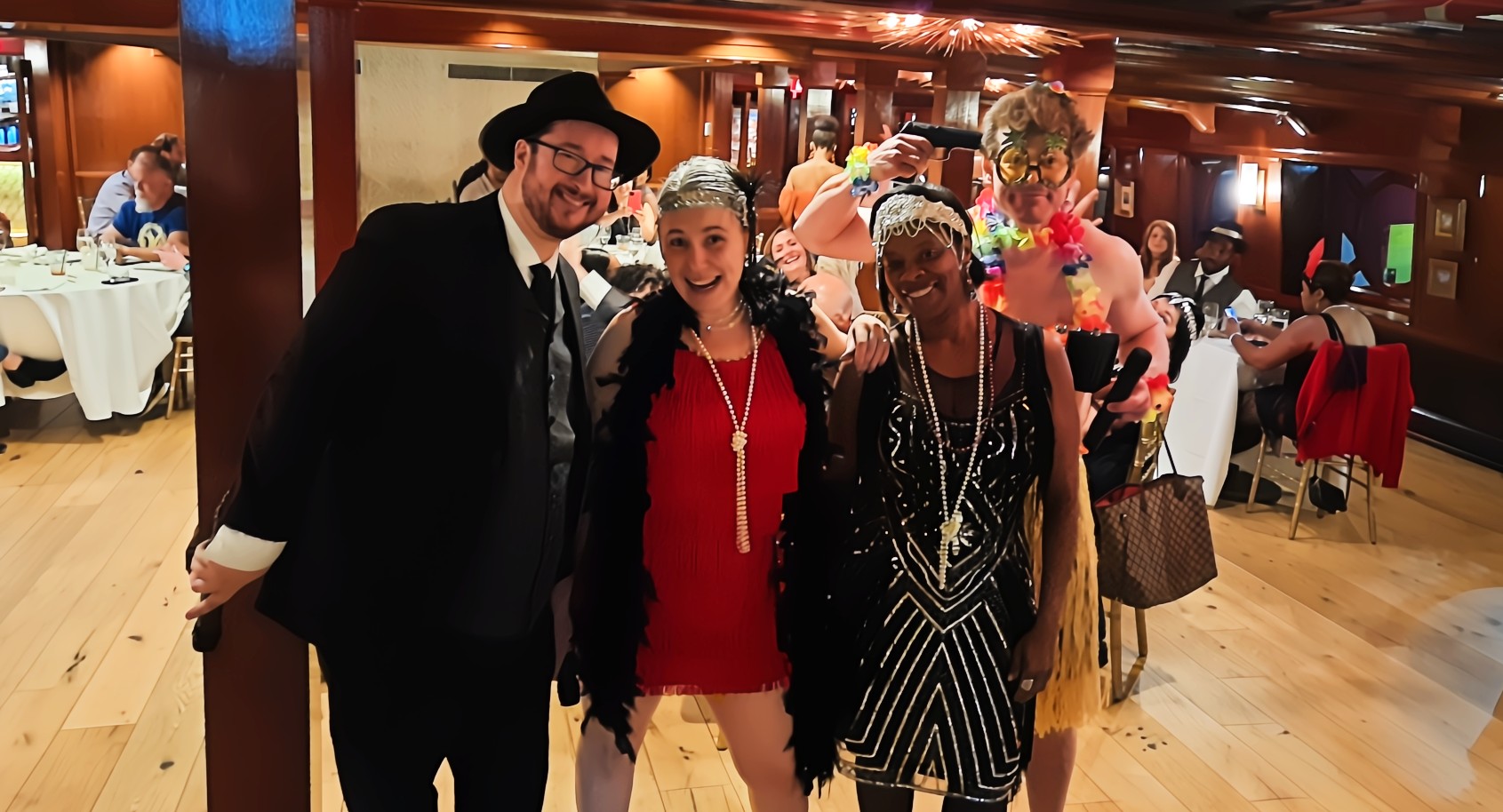 Guests in elegant 1920s attire posing with actors at a typical murder mystery party, celebrating the theme
