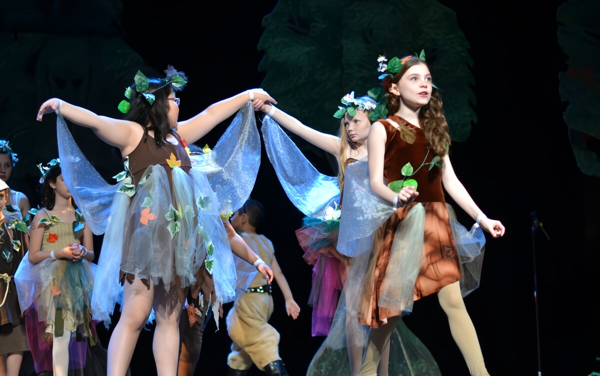 Children in colorful costumes rehearsing for a community theater play in NJ