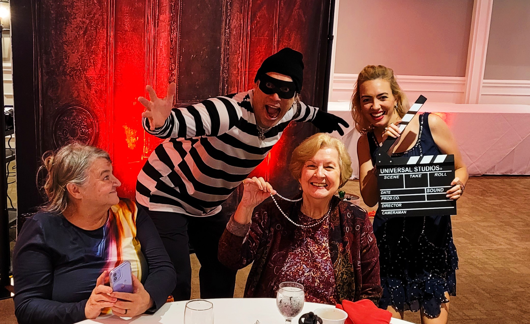 A group of actors and guests posing together at a typical murder mystery party, dressed in themed costumes