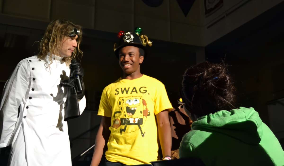 A group of college friends laughing while interrogating a suspect at a murder mystery night on campus