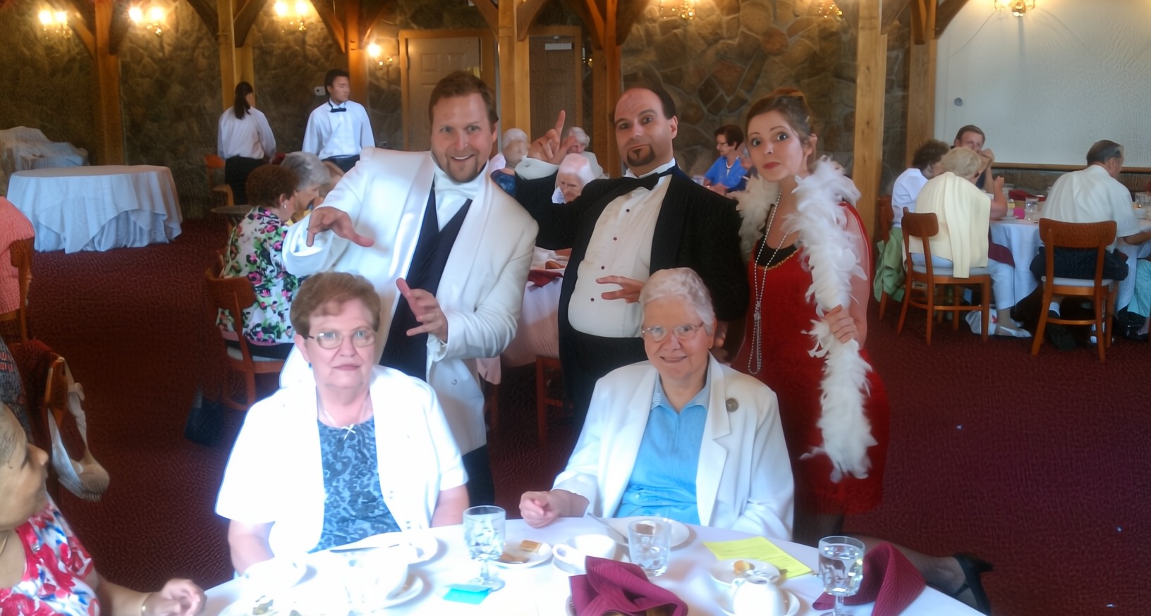 A costumed Houdini actor surrounded by suspects in a comedic murder mystery show full of suspense and humor