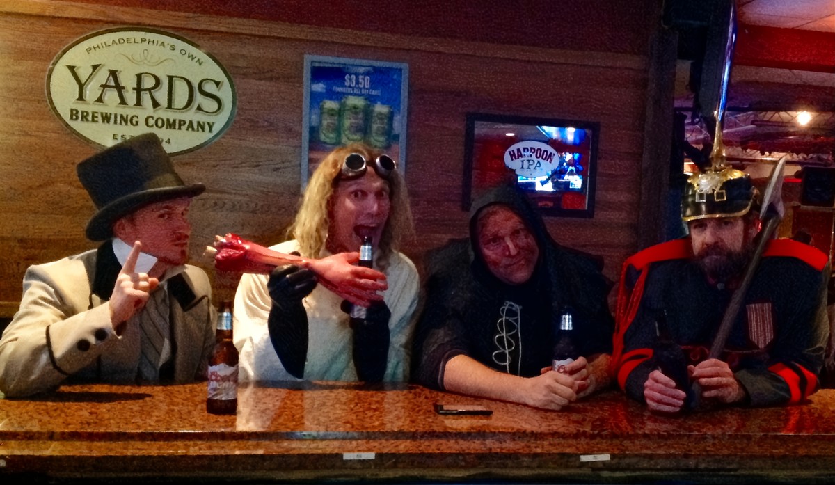 Actors portraying Dr. Frankenstein, Igor, The Baron, in full costume, sharing drinks and laughter at a dimly lit bar in New Jersey