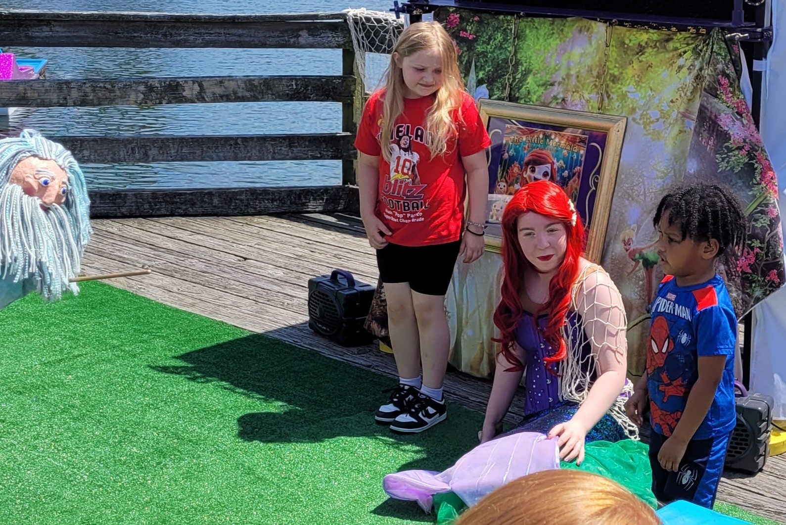 An actor in a shimmering Little Mermaid costume posing with excited kids after a puppet show in Historic Smithville
