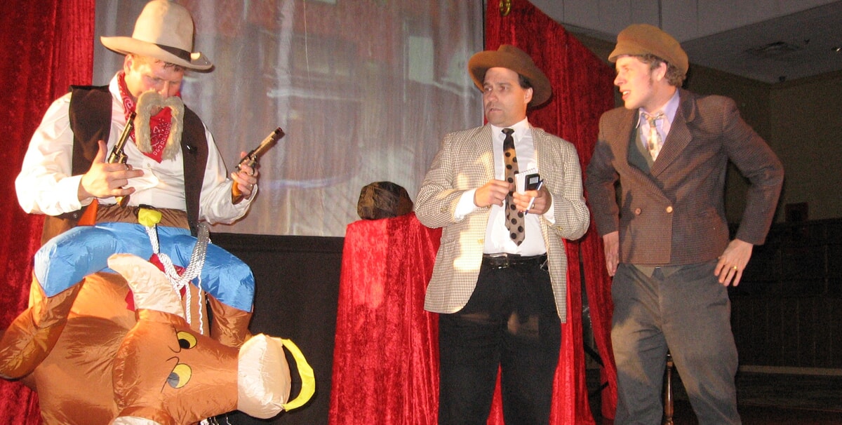 An audience laughing while watching a comedic murder mystery scene